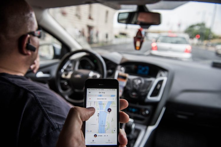A passenger holds an Apple Inc. iPhone displaying the Uber Technologies Inc. car service taxi application (app) journey progress screen in this arranged photograph in Budapest, Hungary, on Wednesday, July 13, 2016. Uber will suspend its ride-hailing services in Hungary from July 24 following a government decision to pass a bill that allows authorities to block access to the mobile application and fine media promoting it. Photographer: Akos Stiller/Bloomberg
