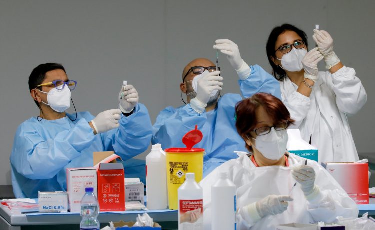 FILE PHOTO: Health workers prepare doses of the Pfizer-BioNTech COVID-19 vaccine at an inoculation centre in Naples, Italy, January 8, 2021. REUTERS/Ciro De Luca
