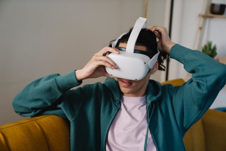 man putting on vr goggles on sofa at home