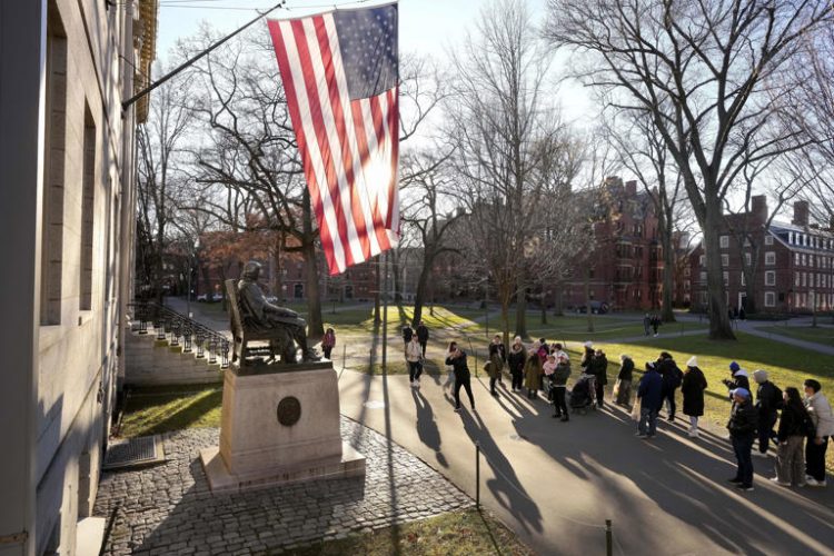 People take photos near a John Harvard statue, left, on the Harvard University campus, Jan. 2, 2024, in Cambridge, Mass. In a letter