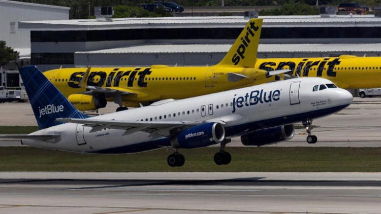 A JetBlue Airlines plane takes off near Spirit Airlines planes.
© Photo: Joe Raedle (Getty Images)