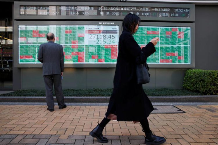 A woman walks past a man examining an electronic board showing Japan's Nikkei average and stock quotations outside a brokerage, in Tokyo, Japan, March 20, 2023. REUTERS/Androniki Christodoulou/File Photo
© Thomson Reuters