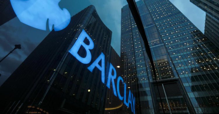 Signage shines through a window reflecting Barclays head office in Canary Wharf, London, U.K.