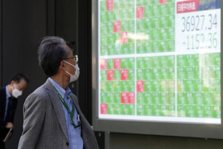 A person looks at a stock board showing Japan's Nikkei 225 index in Tokyo on April 19, 2024. Asian benchmarks extended gains Tuesday