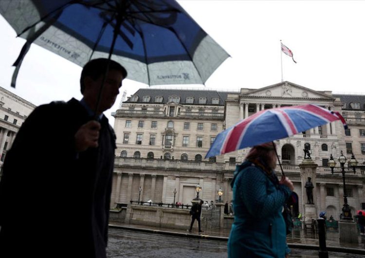 A tourist shelters from the rain under an Union Jack umbrella near the Bank of England in the City of London financial district in London, Britain, February 13, 2024.