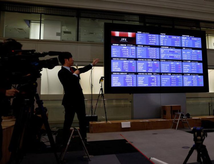 A TV reporters points a closing price of Nikkei index on a stock quotation board after a ceremony marking the end of trading in 2023 at the Tokyo Stock Exchange (TSE) in Tokyo, Japan December 29, 2023