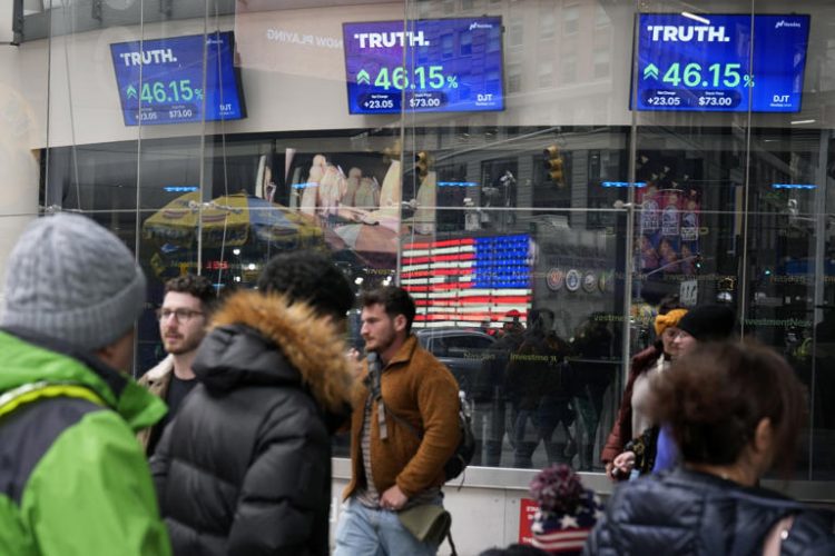 Pedestrians walk past the Nasdaq building as the stock price of Trump Media & Technology Group Corp. is displayed on screens, March 26, 2024, in New York. On Friday, May 3, Trump Media and Technology Group, the owner of social networking site Truth Social, fired BF Borgers, an auditor that federal regulators recently charged with “massive fraud.”