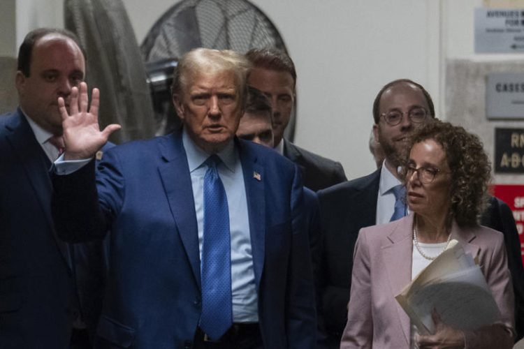 Former President Donald Trump waves during a break at the Manhattan criminal court in New York.