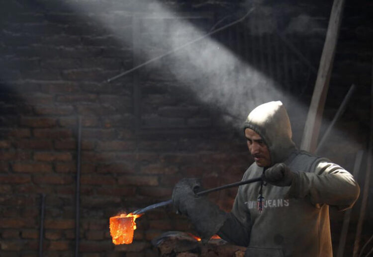 A worker carries a crucible of melted copper as he makes statues at a workshop in Lalitpur, Nepal December 23, 2015. REUTERS/Navesh Chitrakar/File Photo