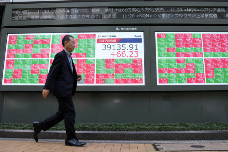 A person walks past an electronic stock board showing Japan's Nikkei 225 index, center, at a securities firm Tuesday, May 21, 2024 in Tokyo. Asian shares mostly fell Tuesday, even as most U.S. stock indexes finished higher, especially technology issues like Nvidia.