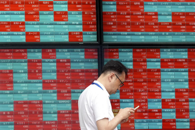 A person stands in front of an electronic stock board showing Japan's Nikkei index at a securities firm in Tokyo, on May 28, 2024. Asian shares traded mixed Wednesday, June 5, 2024, as investors weighed recent data highlighting a slowing U.S. economy that offers both upsides and downsides for Wall Street.