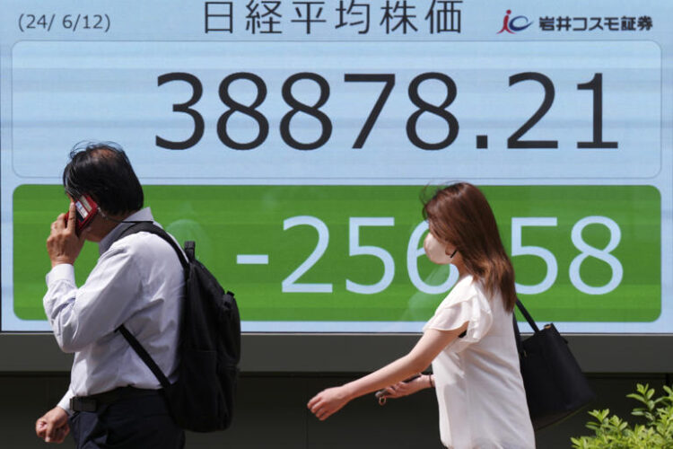 People walk in front of an electronic stock board showing Japan's Nikkei 225 index at a securities firm Wednesday, June 12, 2024, in Tokyo. (AP Photo/Eugene Hoshiko)