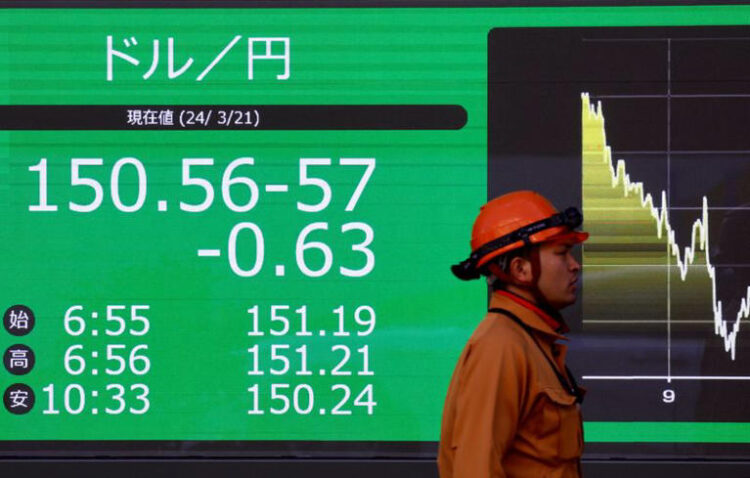 A man walks past an electric screen displaying the current Japanese Yen exchange rate against the U.S. dollar outside a brokerage in Tokyo, Japan March 21, 2024. REUTERS/Issei Kato/File Photo