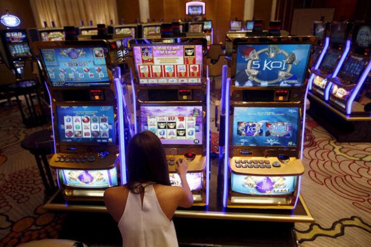 A casino trainee demonstrates how to play a slot machine in the Philippines, April 16, 2015. REUTERS/Erik De Castro/File Photo