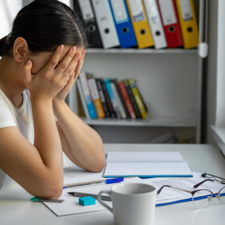 University student sadeness alone while sitting on table doing homework