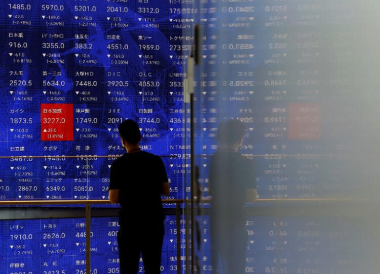 A man stands next to an electronic stock quotation board inside a building in Tokyo, Japan August 2, 2024. REUTERS/Issei Kato/File Photo