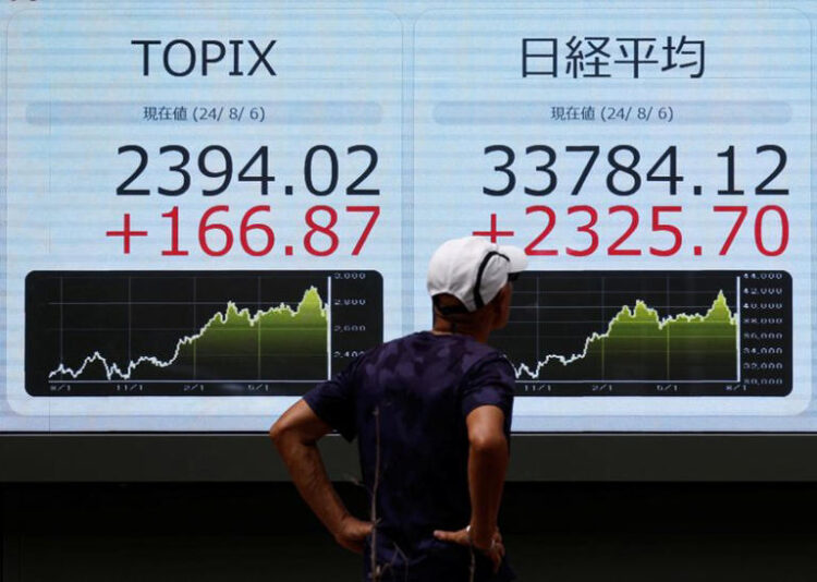 A man looks at an electronic board displaying Topix and Japan's Nikkei share averages outside a brokerage in Tokyo, Japan, August 6, 2024. REUTERS/Willy Kurniawan/File Photo